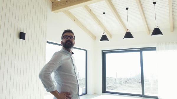 A mature man looking around unfurnished house, moving in new home concept.