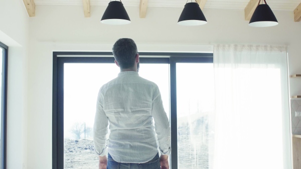 A mature man looking around unfurnished house, moving in new home concept.