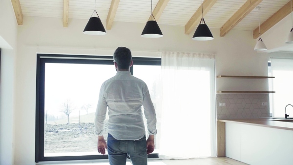 A mature man looking around unfurnished house, moving in new home concept. Slow motion.