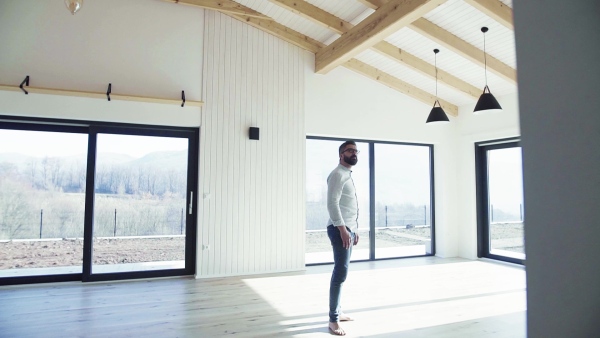 A mature man looking around unfurnished house, moving in new home concept. Slow motion.