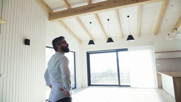 A mature man looking around unfurnished house, moving in new home concept. Slow motion.