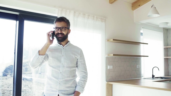 Mature man with smartphone in unfurnished house, moving in new home concept. Slow motion.