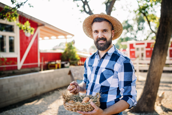 A mature man outdoors on family farm, holding basket with eggs.