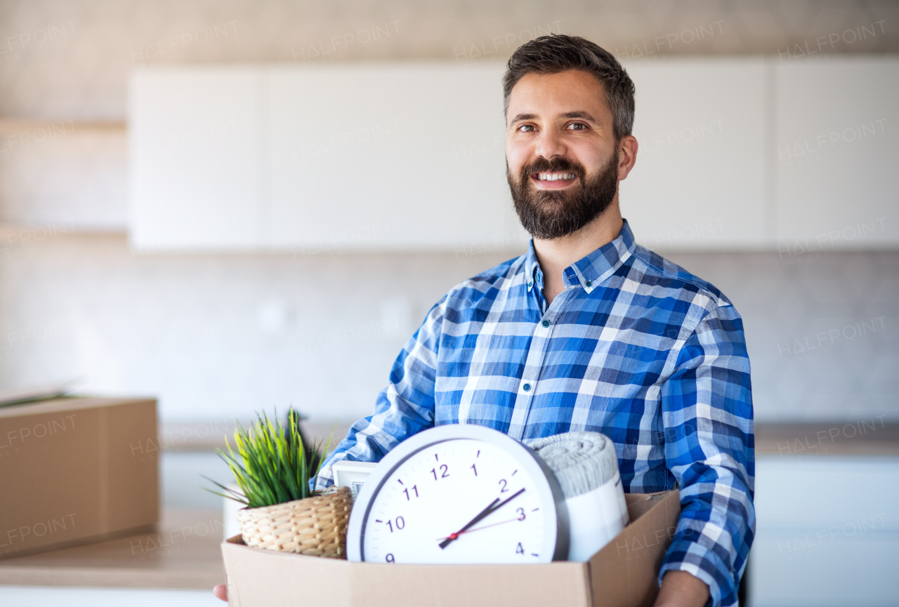 A portrait of mature man with box moving in new unfurnished house.