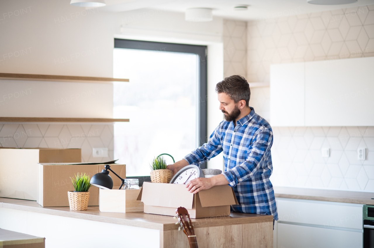 A mature man with boxes moving in new unfurnished house, unpacking.