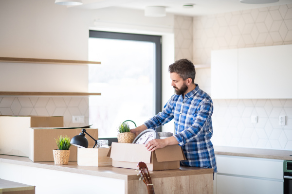 A mature man with boxes moving in new unfurnished house, unpacking.