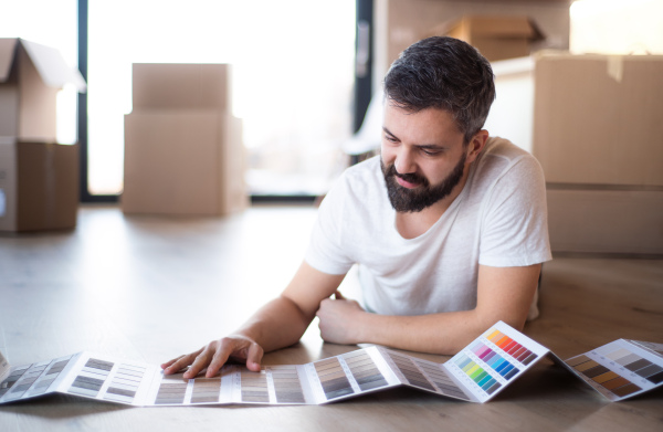 A mature man with boxes moving in new house, looking at color swatch.