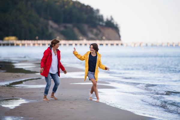 A Senior woman and her preteen granddaughter running and having fun on sandy beach.