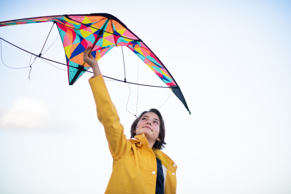 A low angle view of happy preteen girl preparing kite for flying outdoors.