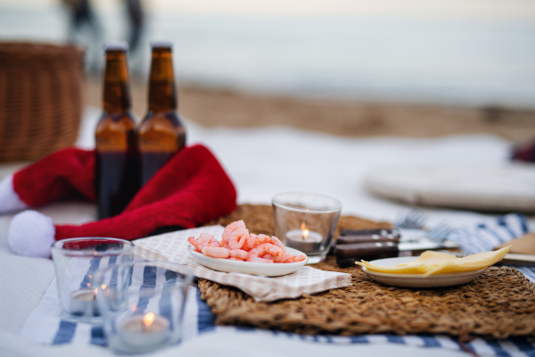 A beach picnic with schripms, beer, candles and santa hat. Exotic new year and Christmas