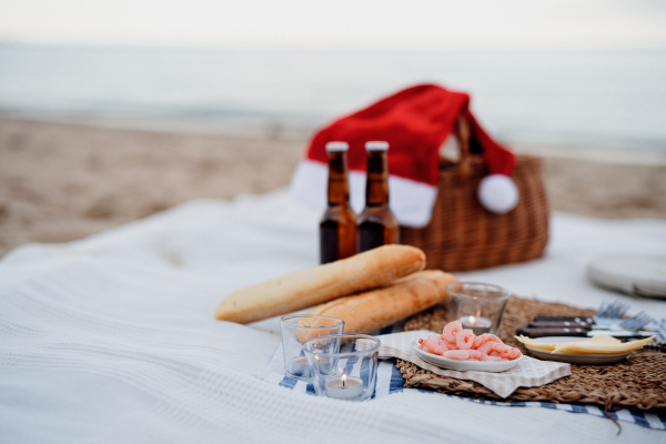 A beach picnic with shripms, beer, candles and santa hat. Exotic new year and Christmas