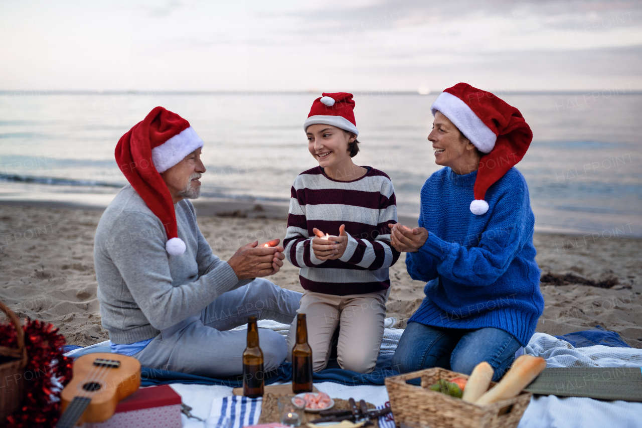 A senior couple with granddaugter celebrate New Year or Christmas and have picnic on beach.