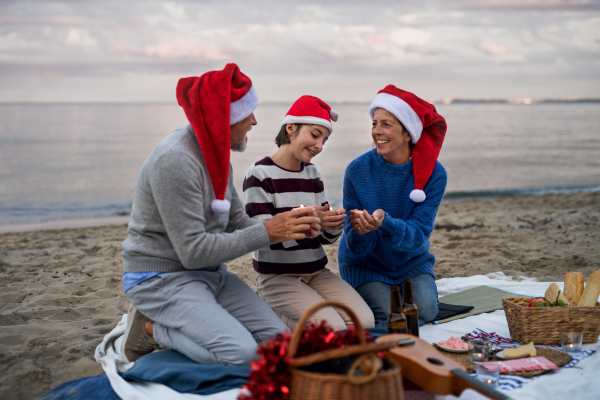 A senior couple with granddaugter celebrate New Year or Christmas and have picnic on beach.