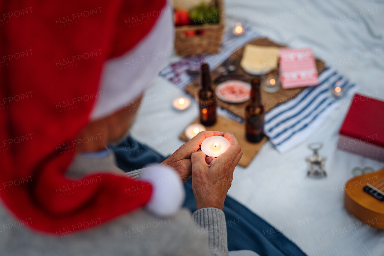 Close up of unrecognizable senior woman in santa hat holding candle and celebrate New Year or Christmas on beach