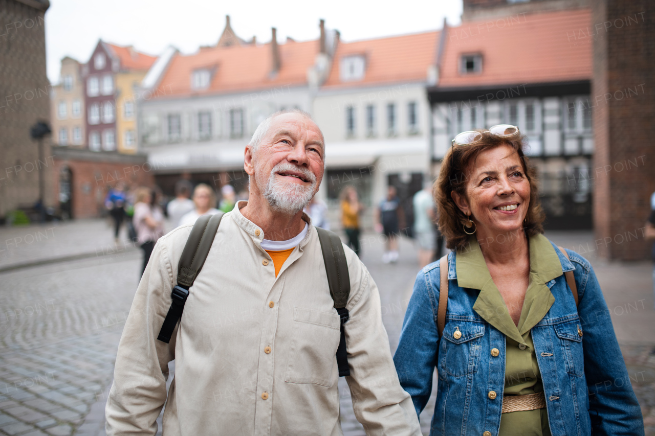 A portrait of happy senior couple tourists outdoors in historic town