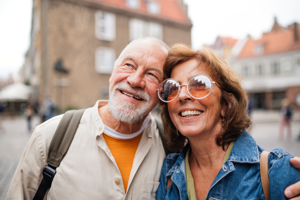 Close up portrait of happy senior couple tourists hugging on trip in town