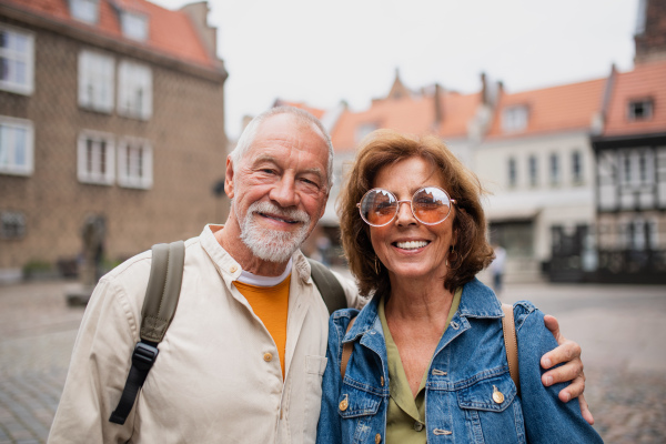 A happy senior couple tourists outdoors in historic town