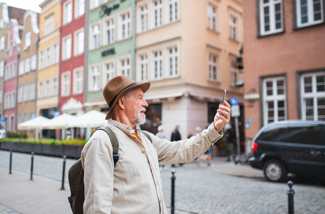 A portrait of happy senior man tourists taking selfie outdoors in historic town