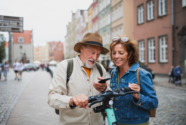 A portrait of happy senior couple tourists riding scooter together outdoors in town