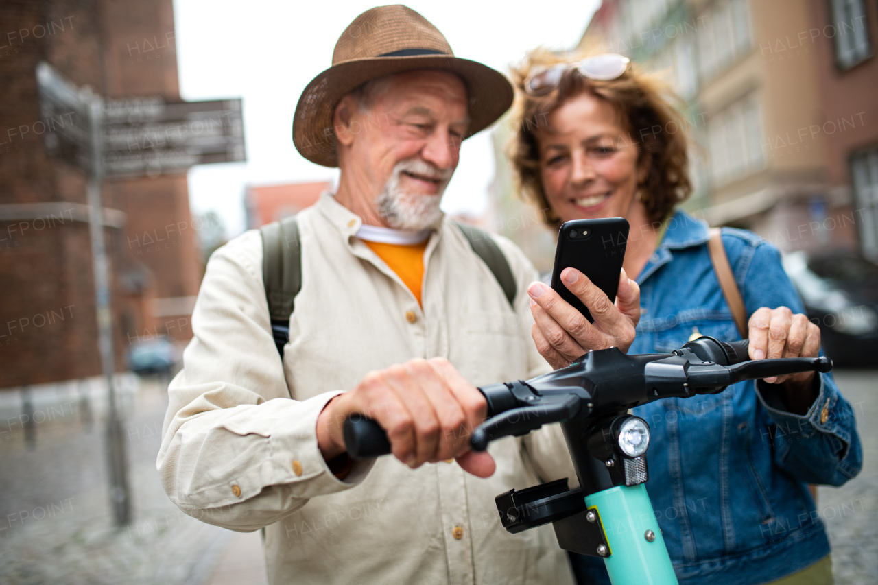 A close up of happy senior couple tourists scanning code to rent a scooter together outdoors in town