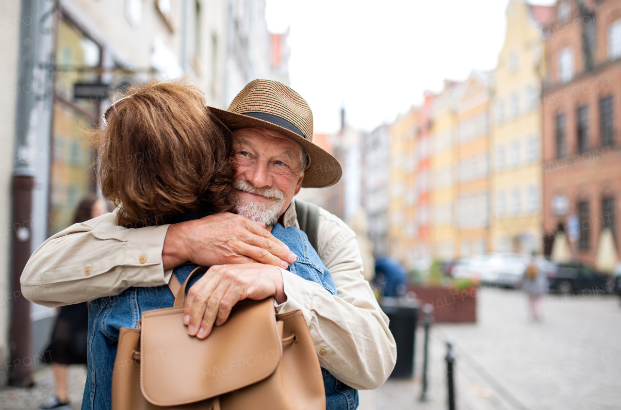 A portrait of happy senior couple tourists hugging outdoors in historic town