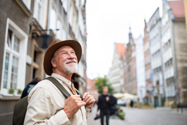 A senior man tourist outdoors sightseeing in historic town.