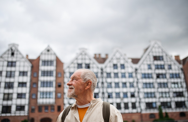 A senior man tourist outdoors sightseeing in historic town.