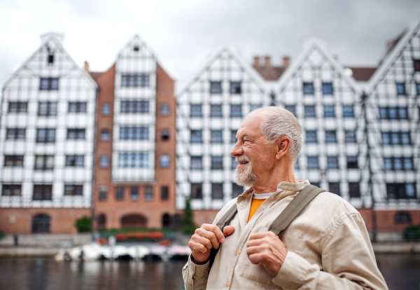 A senior man tourist outdoors sightseeing in historic town.