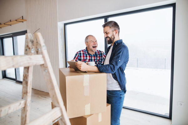 A cheerful senior man helping his mature son with furnishing new house, a new home concept.