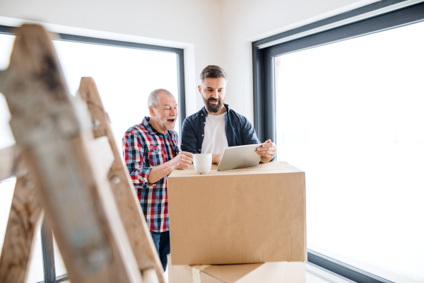 A cheerful senior man helping his mature son with furnishing new house, a new home concept.