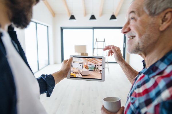 A cheerful senior man with tablet helping his mature son with furnishing new house, a new home concept.