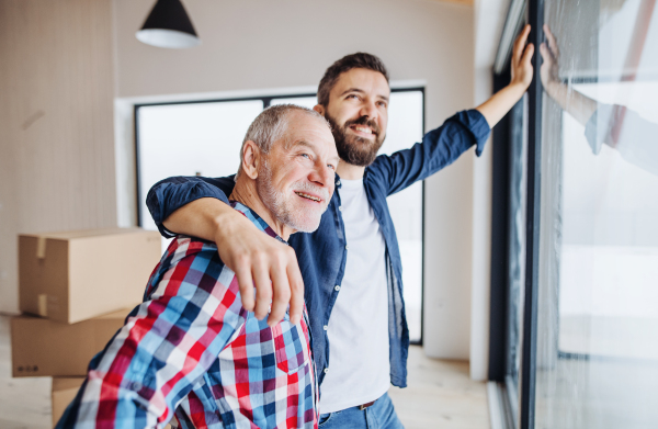 A cheerful senior man helping his mature son with furnishing new house, a new home concept.