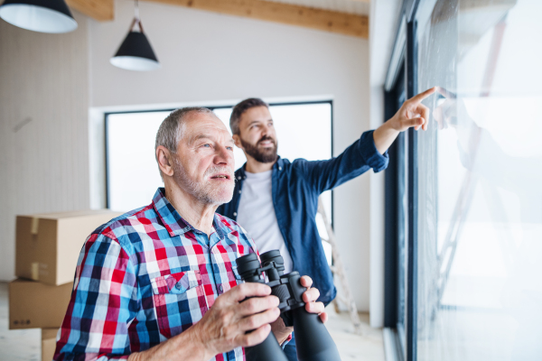 A cheerful senior man helping his mature son with furnishing new house, a new home concept.