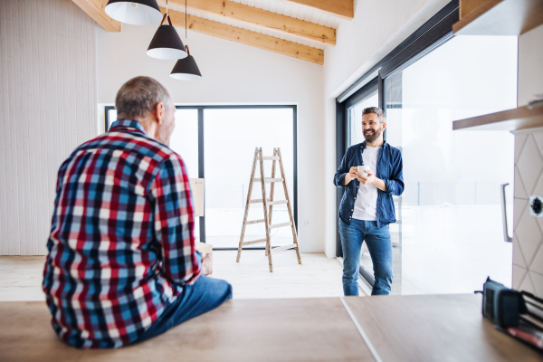 A portrait of mature man with his senior father drinking coffee when furnishing new house, a new home concept. Copy space.