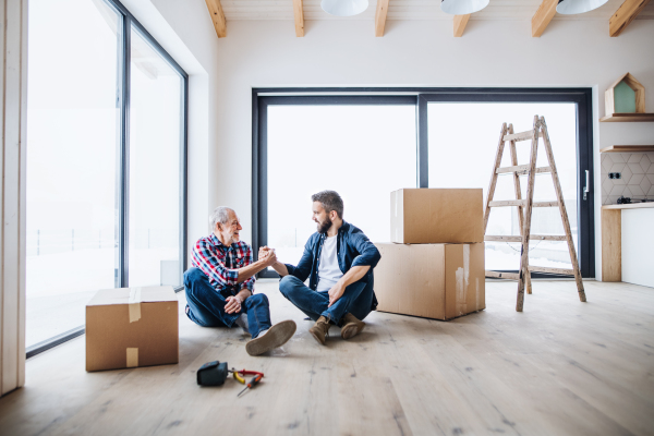 A portrait of mature man with his senior father shaking hands when furnishing new house, a new home concept. Copy space.