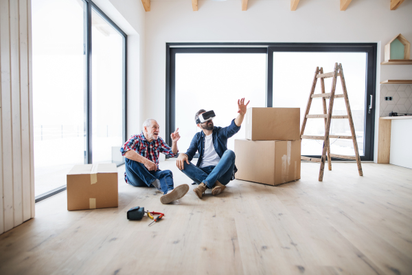 A mature man with VR goggles and his senior father furnishing new house, a new home concept.