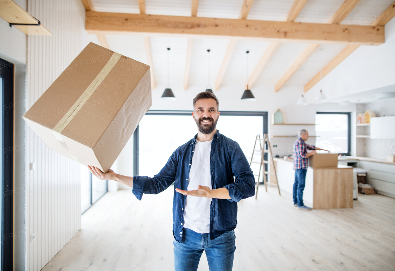 A mature man holding a large box in one hand when furnishing new house, a new home concept.