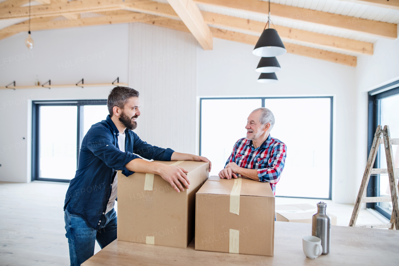 A cheerful senior man helping his mature son with furnishing new house, a new home concept.