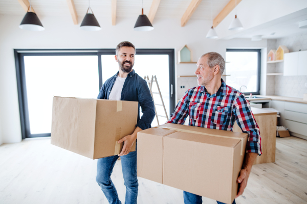 A cheerful senior man helping his mature son with furnishing new house, a new home concept.