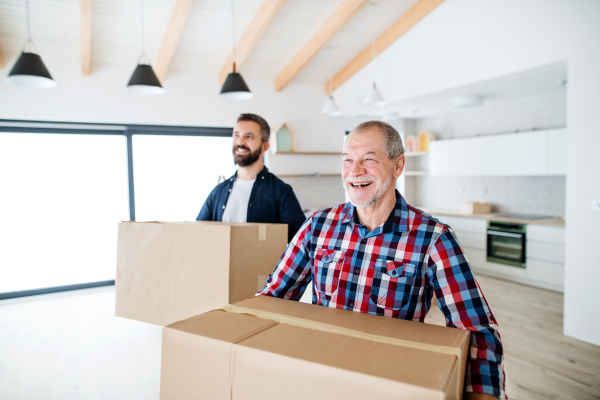 A cheerful senior man helping his mature son with furnishing new house, a new home concept.