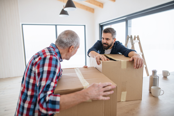 A cheerful senior man helping his mature son with furnishing new house, a new home concept.