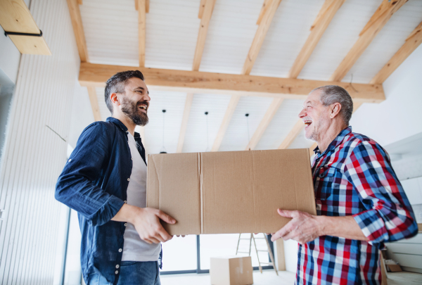 A cheerful senior man helping his mature son with furnishing new house, a new home concept.