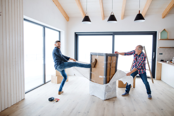 A cheerful senior man helping his mature son with furnishing new house, a new home concept.