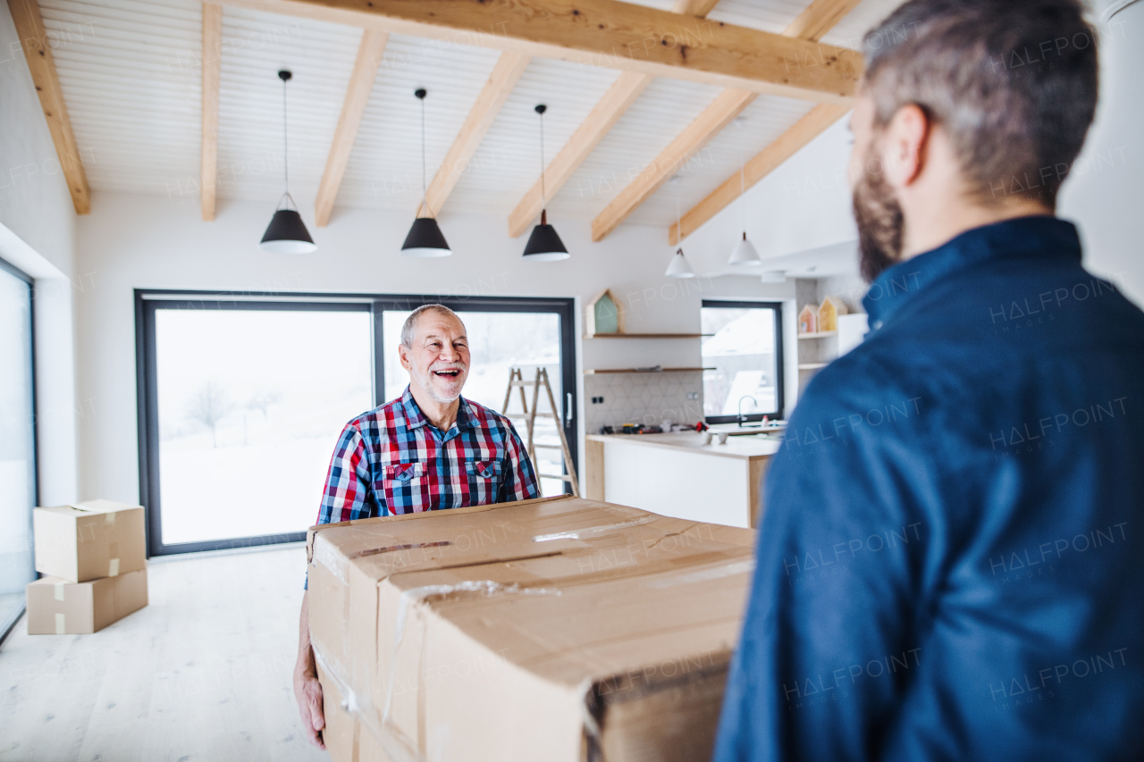 A cheerful senior man helping his mature son with furnishing new house, a new home concept.