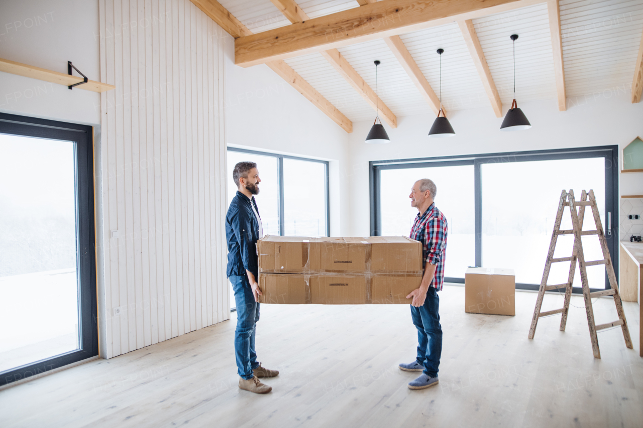 A cheerful senior man helping his mature son with furnishing new house, a new home concept.