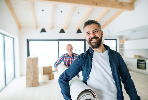 A cheerful senior man helping his mature son with furnishing new house, a new home concept.