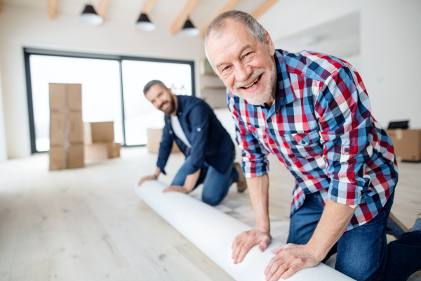 A cheerful senior man helping his mature son with furnishing new house, a new home concept.