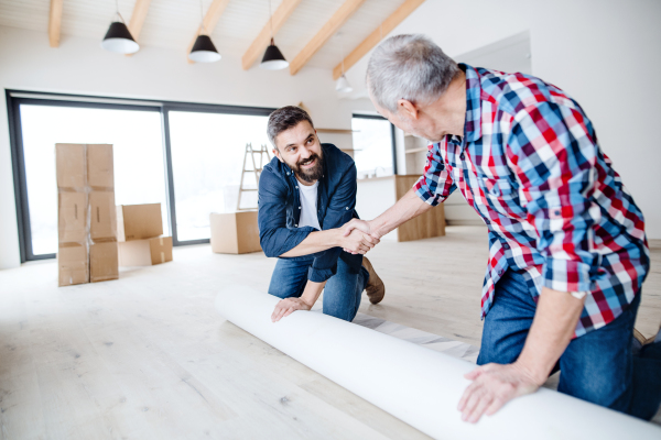 A cheerful senior man helping his mature son with furnishing new house, a new home concept.