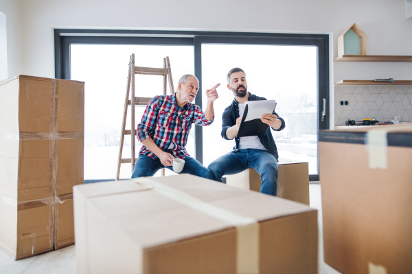 A cheerful senior man helping his mature son with furnishing new house, a new home concept.