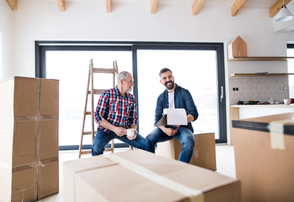 A cheerful senior man helping his mature son with furnishing new house, a new home concept.